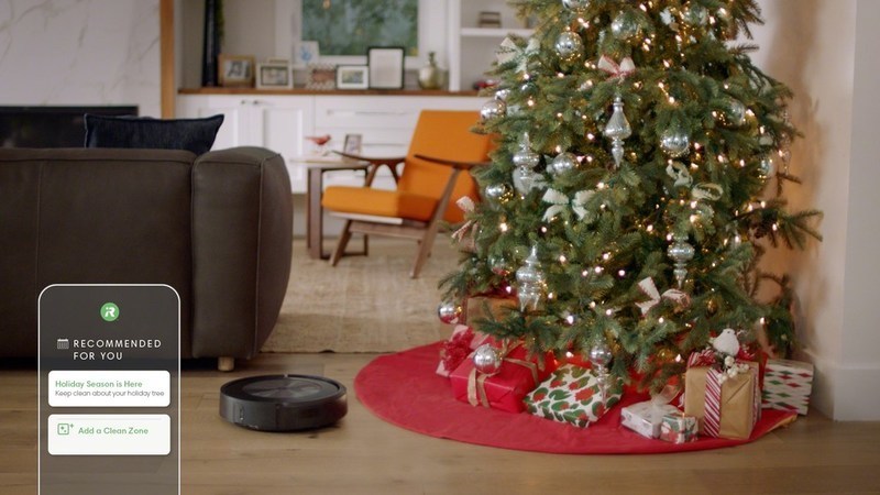 O robô aspirador de pó Roomba J7 da iRobot perto de uma árvore de Natal.