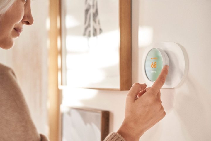 Woman adjusting a Google Nest Smart Programmable Wifi Thermostat. 