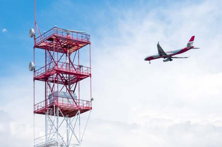 Passenger airlines flying past a large radio communications tower.