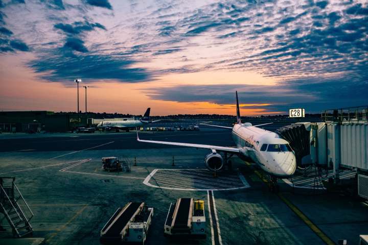 Avión aparcado en la pista del aeropuerto con la puesta de sol de fondo.