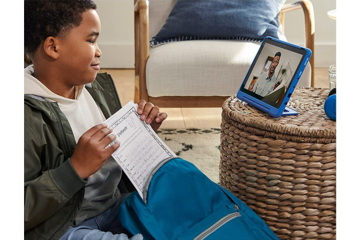 پسری با یک کاربرگ در حال تماشای ویدیویی در Amazon Fire HD 10 Kids Pro آبی رنگ است.