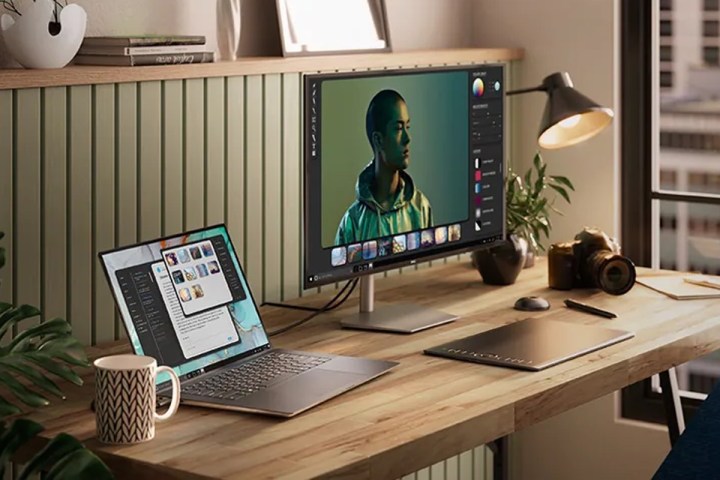 یک لپ تاپ Dell XPS 15 Touch که روی میز کنار مانیتور و سایر لوازم جانبی آموزشی قرار گرفته است.