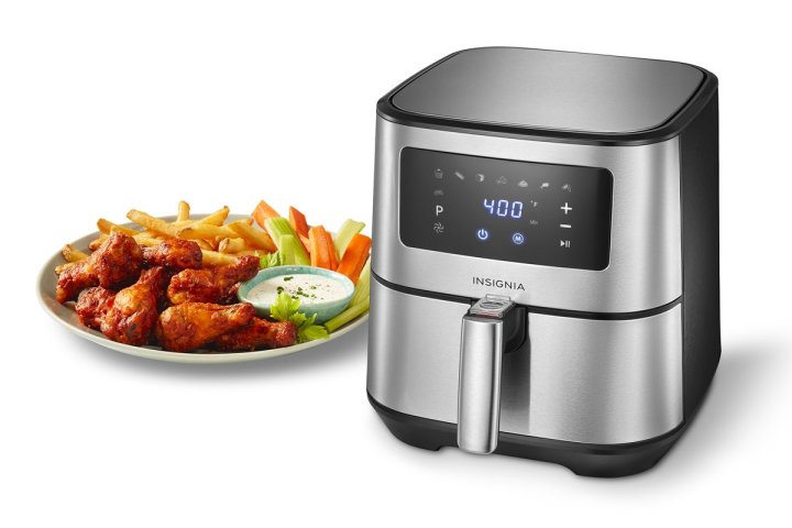 Insignia 5-quart digital air fryer next to a platter of air-fried chicken wings, french fries, veggies and dip. 