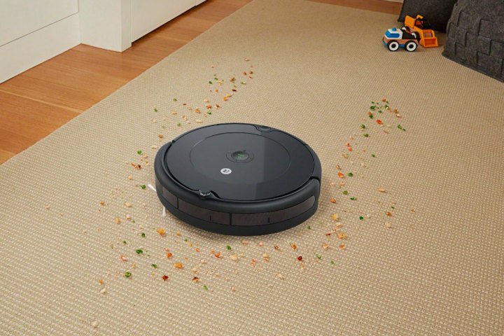 A iRobot Roomba 694 vacuuming up crumbs on a rug.