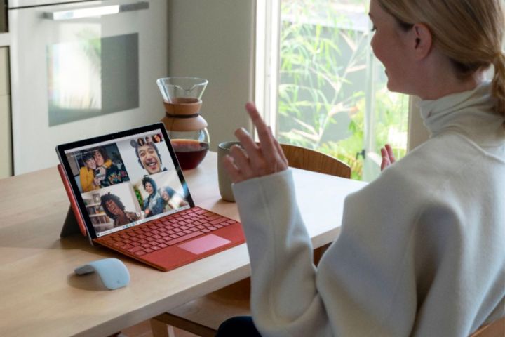 A woman sits at a desk while video chatting using a Microsoft Surface Pro 7.