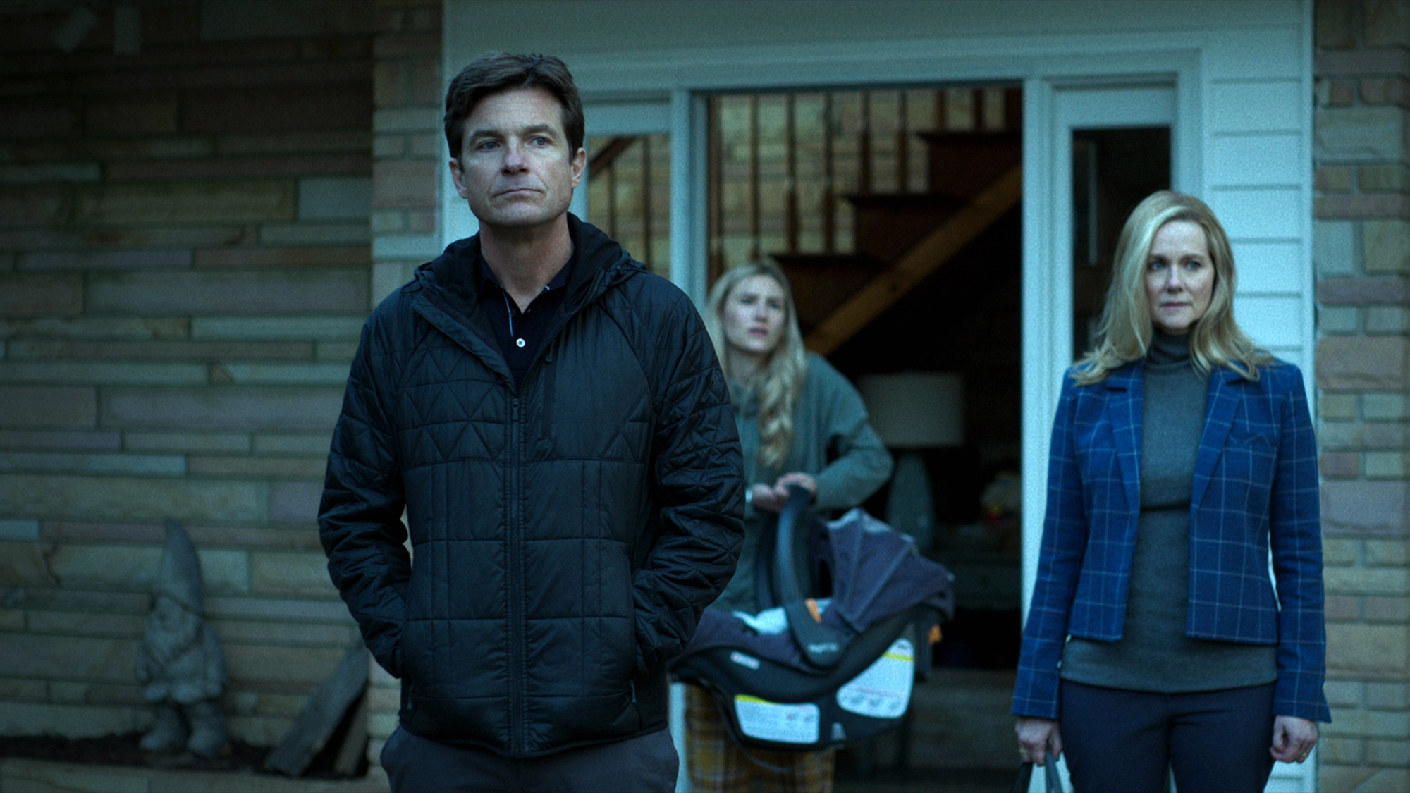 Marty and Wendy Byrde standing, looking at something, their daughter in the background in Ozark season 4.