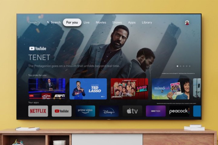 A Sony 65 Class X80J Series LED 4K UHD Smart Google TV mounted on a yellow wall above a media console. 