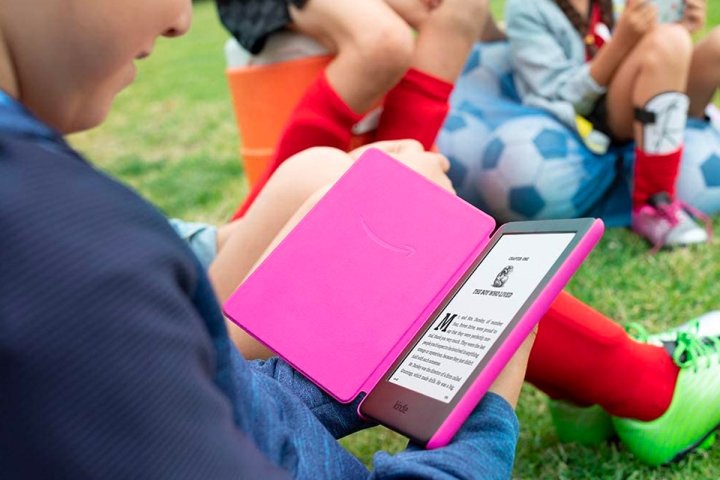 A child reads outside on the Amazon Kindle Kids Edition.