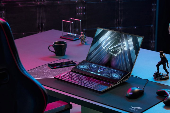 Um ASUS ROG Zephyrus Duo 16 está em uma mesa com iluminação ambiente azul e roxa.