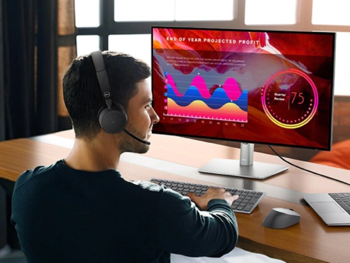 Un hombre que usa los auriculares inalámbricos Dell Pro mientras trabaja en su computadora.