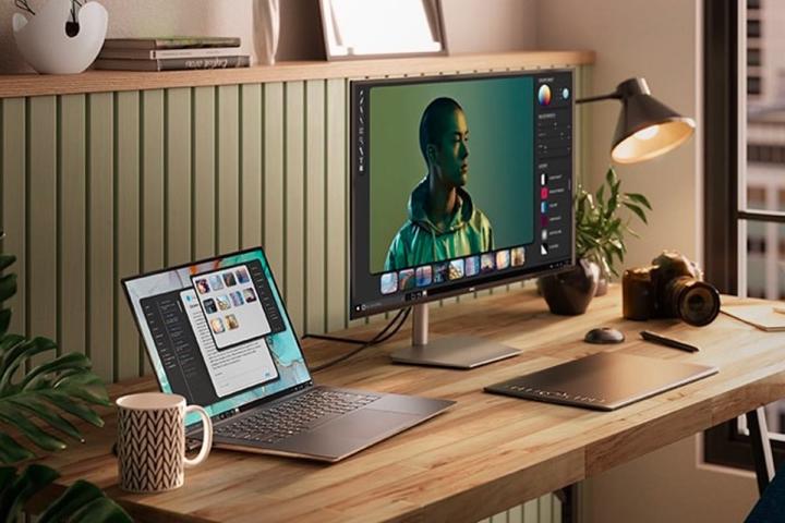 Um laptop Dell XPS 15 Touch fica em uma mesa de escritório ao lado de um monitor externo.