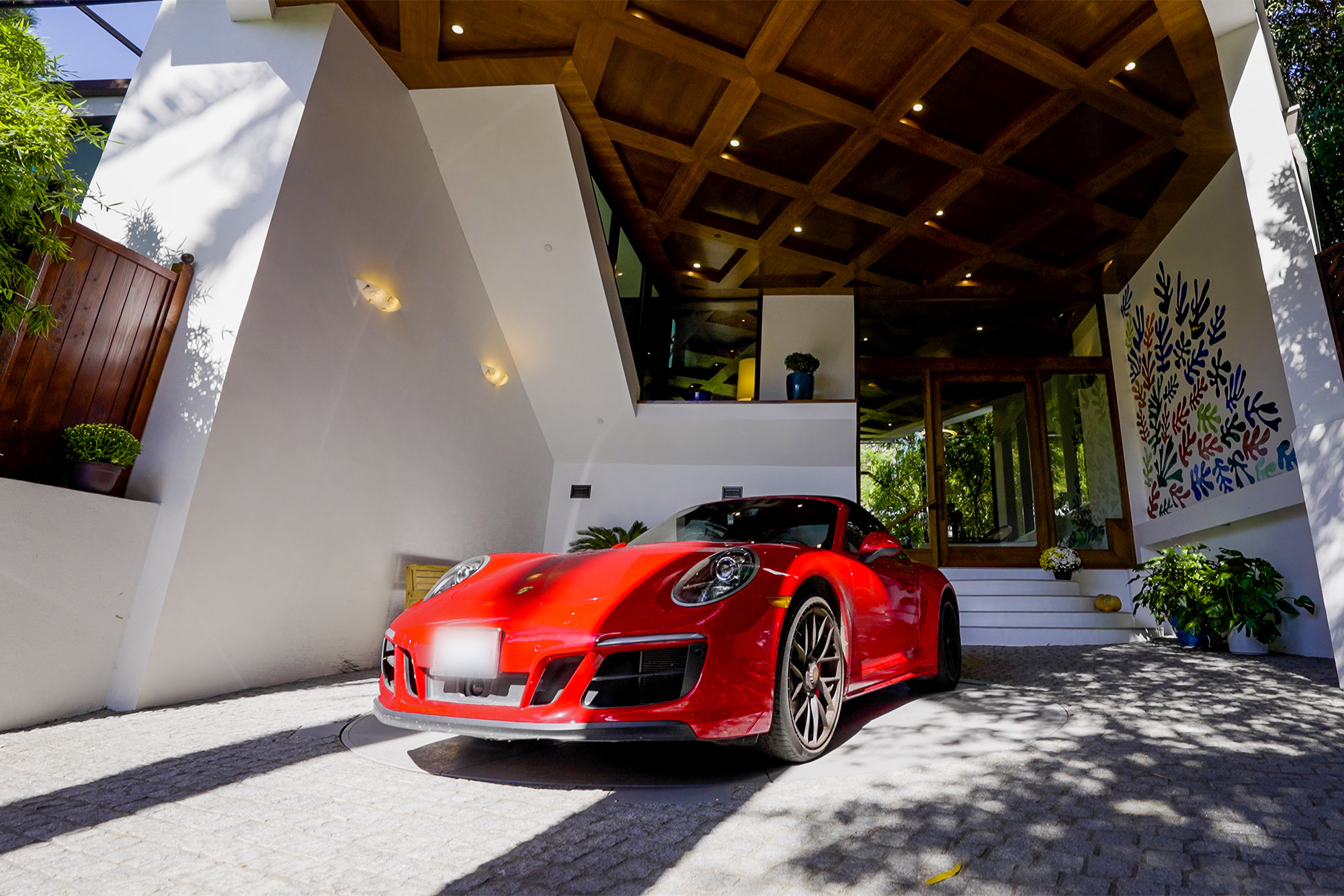 A red sports car turns on a turntable in a driveway.