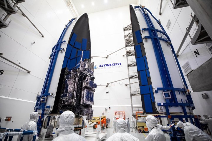 A NOAA weather satellite being placed inside a rocket fairing ahead of launch.
