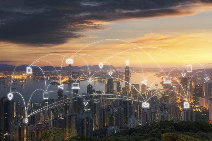 Вид с воздуха на город на закате, иллюстрирующий связь 5G и Wi-Fi между зданиями.