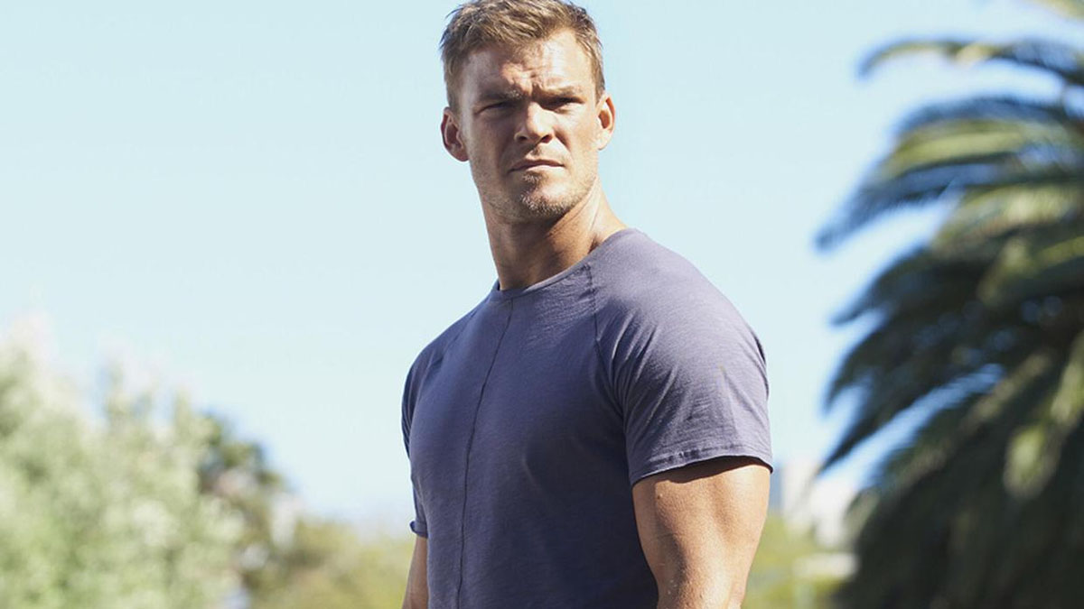 Alan Ritchson as Jack Reacher stares intently at something in Reacher.