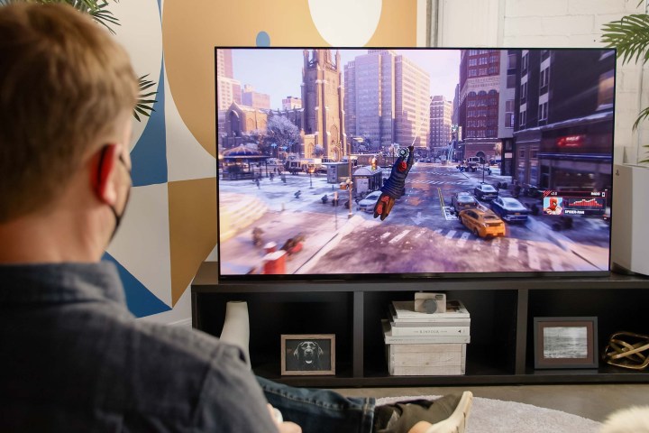 Caleb Denison sits in front of the Sony A95K TV playing Marvel's Spider-Man: Miles Morales on the PS5.