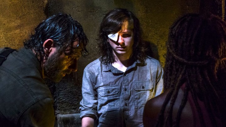 Carl from The Walking Dead in a cave with an eyepatch, looking defeated.