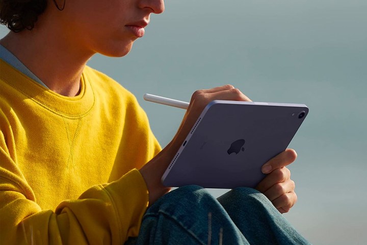 A person writes on a 2021 Apple iPad Mini with an Apple Pencil.