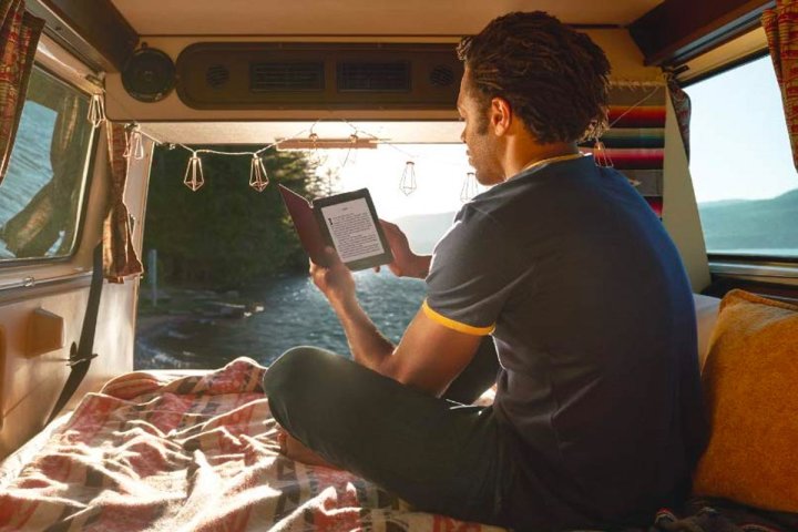 A young man reads a book in his car on the Amazon Kindle Paperwhite.