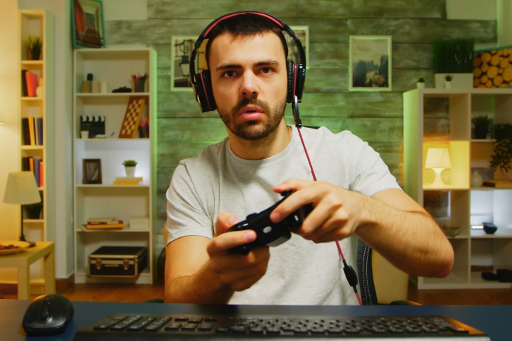 Un uomo siede alla scrivania e gioca a un videogioco davanti a un computer.