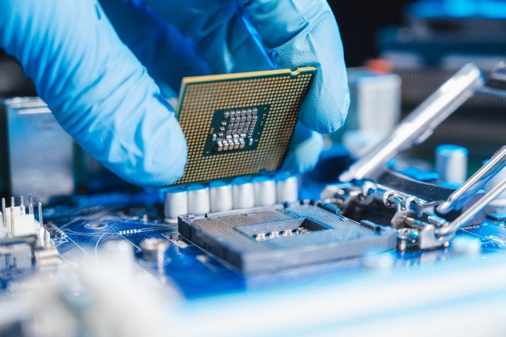 A technician placing a CPU into a motherboard socket for a PC.