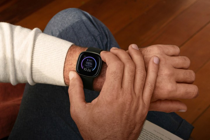 A carbon colored Fitbit Sense is worn on a mans wrist.
