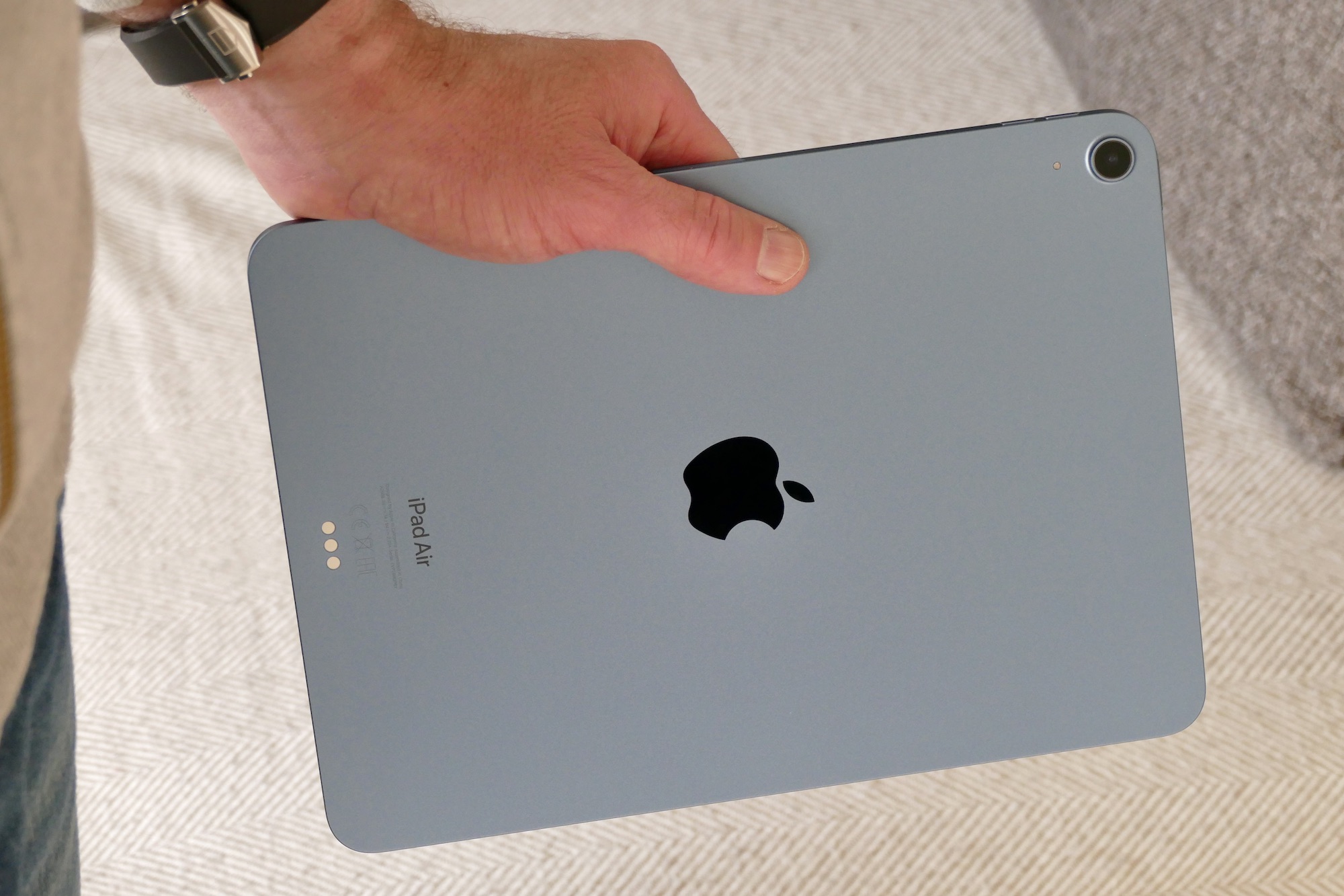 iPad Air 5 seen from the back and held in hand.