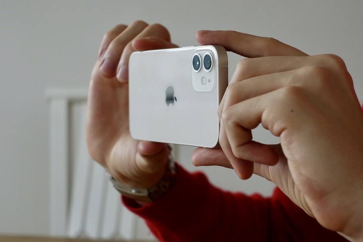 Мужчина нажимает на картинку с помощью iPhone 12.