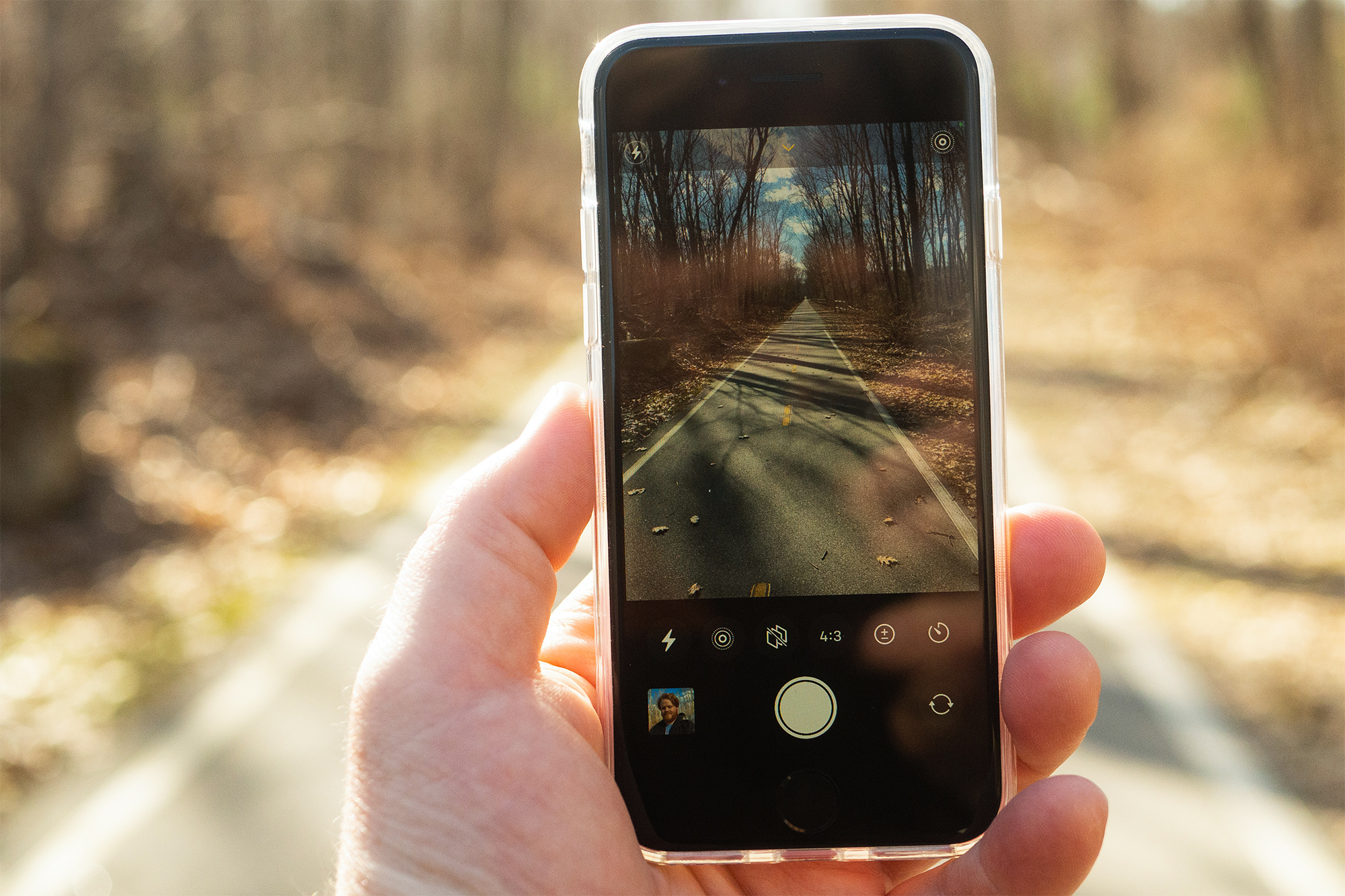 iPhone SE 2022 en la mano en una carretera rural.