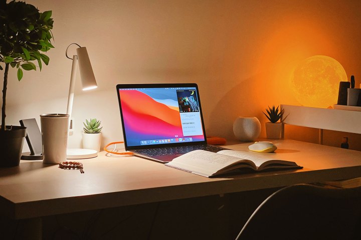 Ein MacBook Air auf einem Schreibtisch mit einem aufgeschlagenen Buch davor.