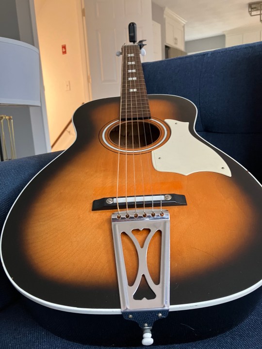 A guitar resting on a couch.
