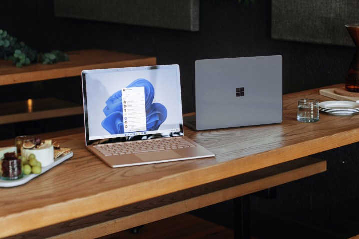 Two windows laptops sit on a wooden table.