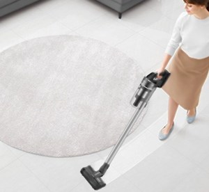 Woman vacuuming living room carget with Samsung Jet 75 Complete Cordless Stick Vacuum.