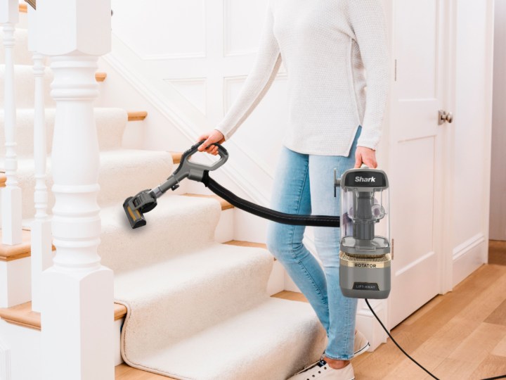 Woman vacuuming stairs with Shark Rotator Lift-Away ADV DuoClean Engage Upright Vacuum.
