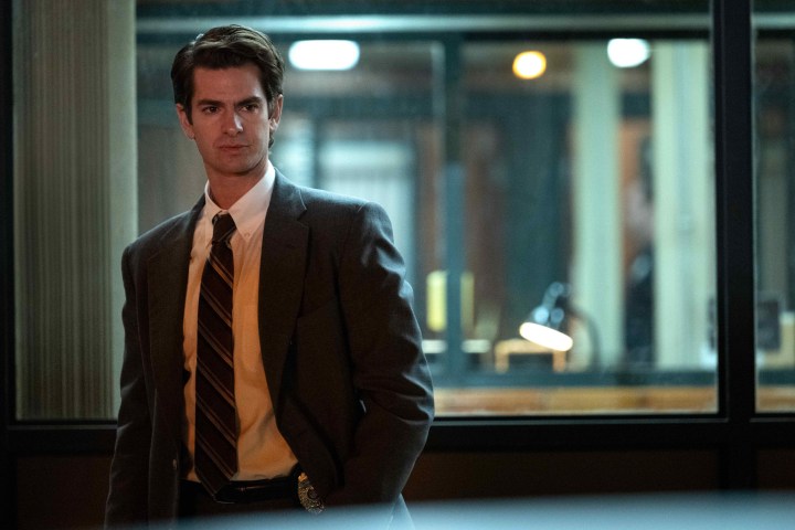 Andrew Garfield stands in front of a police station window in Under the Banner of Heaven.