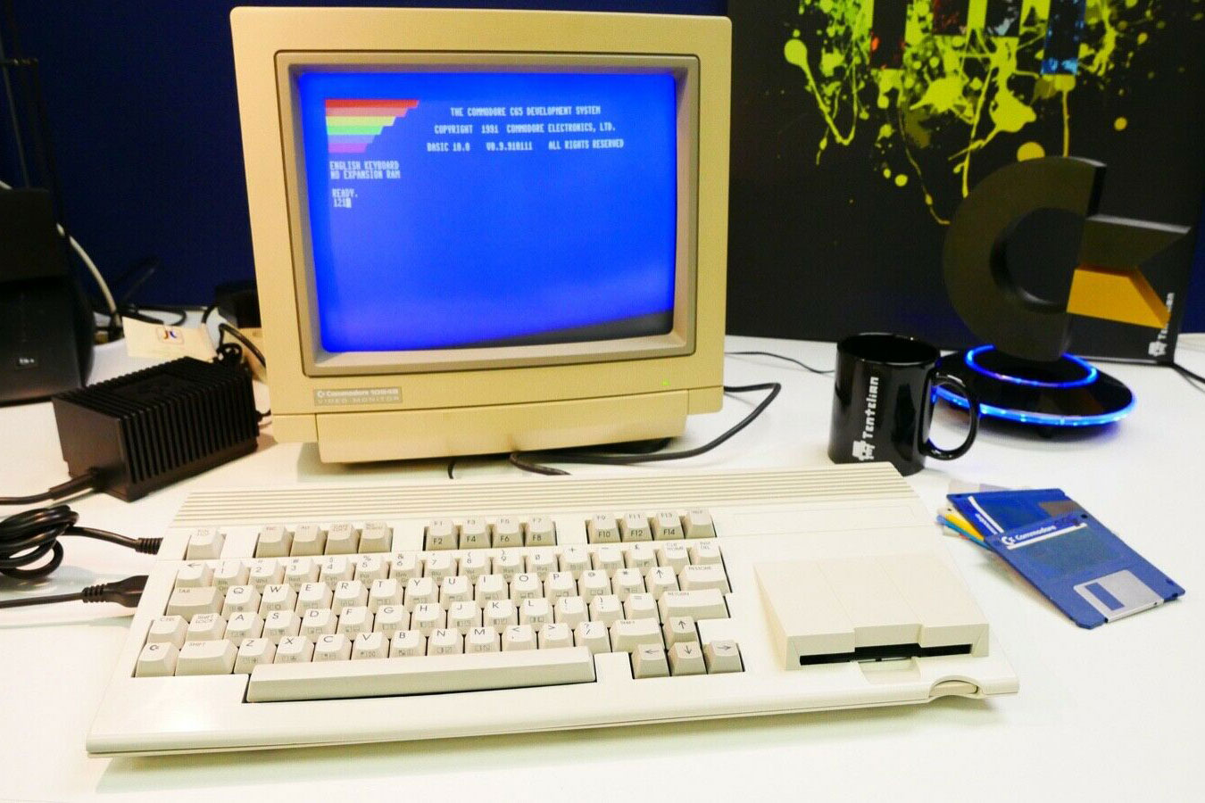 A working Commodore 65 PC on a desk with a monitor and floppy disk.
