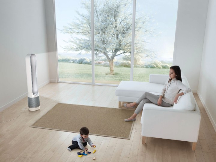 O Dyson Pure Cool Purifying Fan TP01 em uma sala com os pais no sofá e a criança brincando no chão.