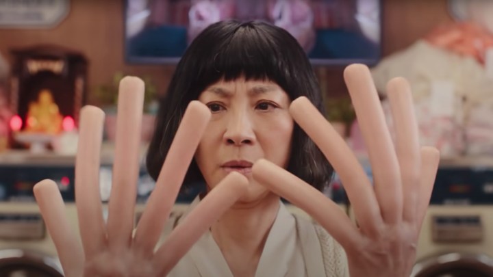 Мишель Йео смотрит на свои пальцы с хот-догом в фильме «Все везде и сразу».
