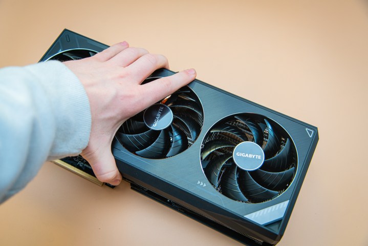 A hand gripping the RTX 3090 Ti graphics card.
