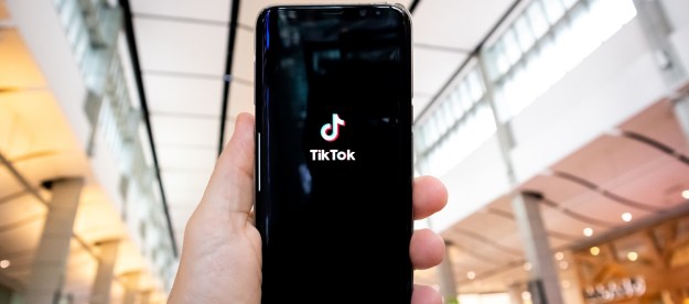 A person's hand holding a phone with the TikTok app on it.