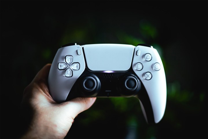 A person holds up a PS5 controller.