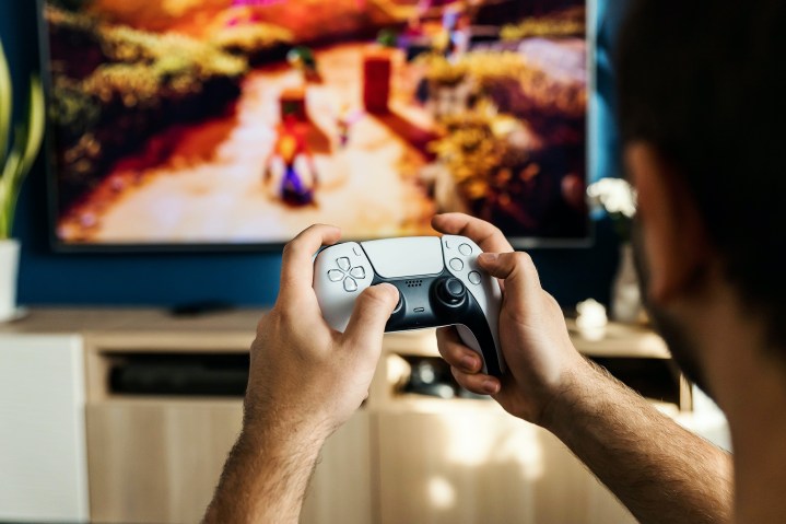 Seseorang memainkan Crash Bandicoot menggunakan pengontrol PS5 DualSense.
