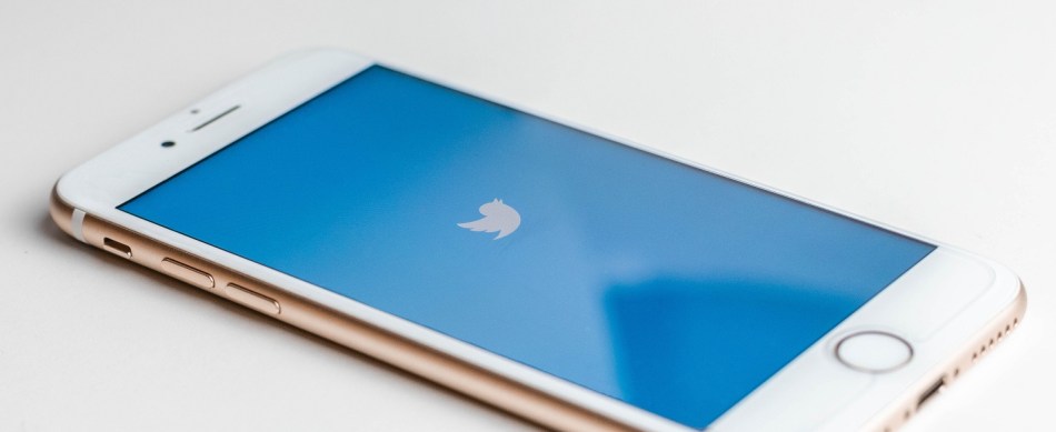 A Twitter icon on a blue background on a smartphone's screen, all on a white background.