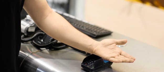 A person using Walletmor chip arm implant to make a payment.