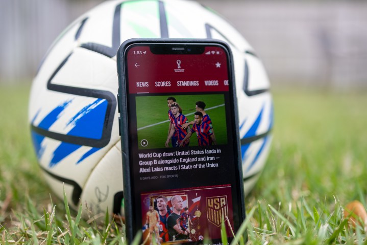 Aplicación Fox Sports en un iPhone frente a un balón de fútbol.