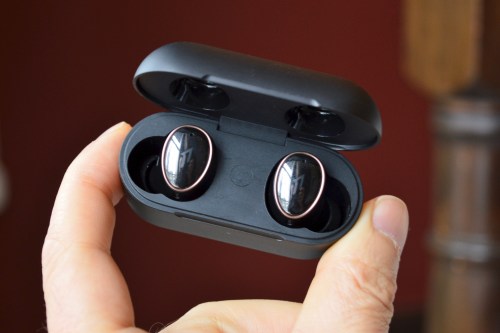 A hand holding the 1More Evo earbuds in their charging case.