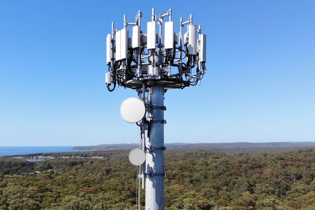 Gran torre celular 5G con múltiples transceptores de ondas milimétricas contra un cielo azul.