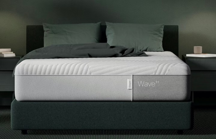 Un materasso Casper Wave Hybrid si trova su un telaio del letto in una camera da letto verde.