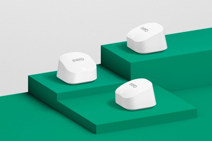 The Eero 6+ mesh Wi-Fi system arrayed on a green surface.