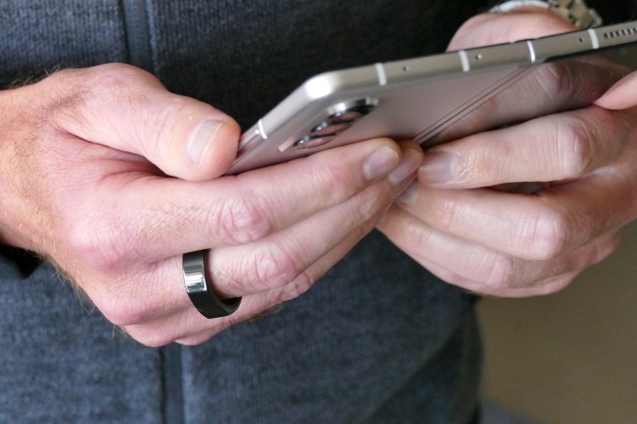 The Oura Ring worn on a man's finger when holding the Galaxy Z Fold 3.